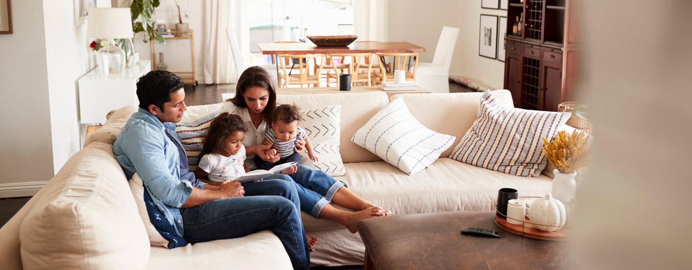 Family sitting on a sofa together looking at a book together